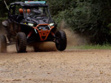 An orange and black UTV speeds across a dirt trail