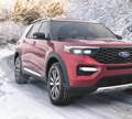 A red Ford Explorer drives on a snowy road with Hercules Avalanche XUV tires. 