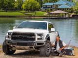 A white Ford car with Hercules Tires in front of a fisherman and a lake. 