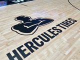 The Hercules Tire logo over a slightly blurry photo of a basketball sitting on the court. 