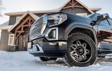 A close-up of a black pickup truck with Hercules Tires’ Avalanche TT winter tires parked in front of a snow-covered house, showcasing the rugged tread pattern designed for extreme winter conditions.