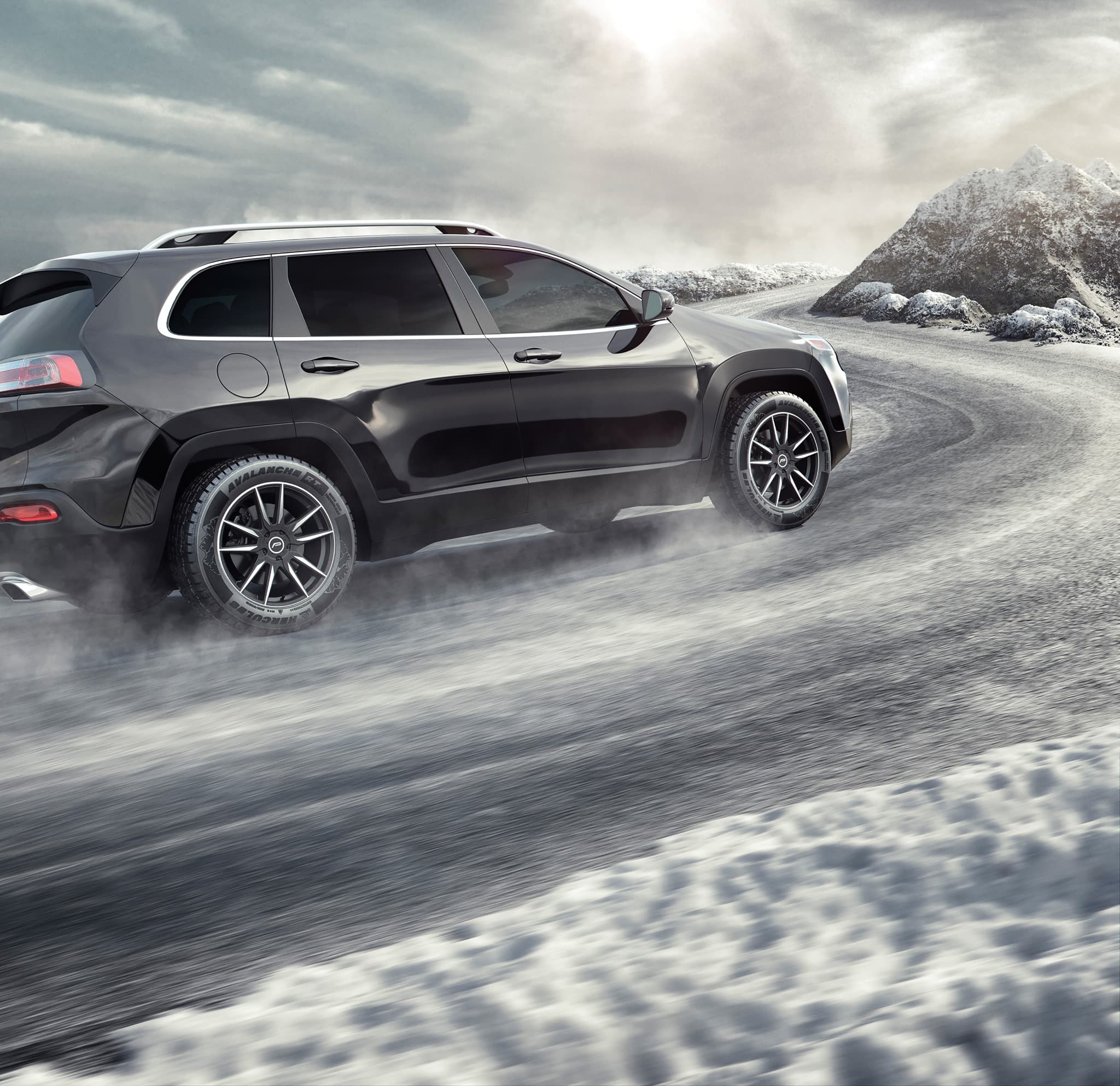 A black car’s passenger side is shown driving up a snowy mountainside outfitted in Hercules Tires AVALANCHE® RTs.
