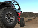 The TIS-UT1 tire is in focus on a red and black UTV in a hilly desert