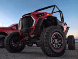 A front angled view of a red and black UTV featuring TIS-UT1 tires